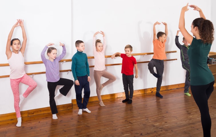 Group of positive european children practicing at the ballet barre